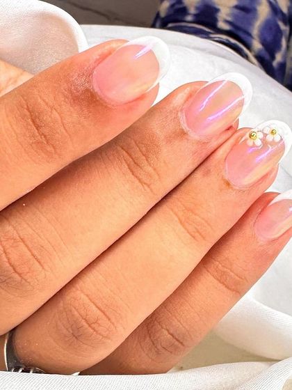 A close-up view of the delicate pearl flower accent. This detail adds a touch of bridal or special occasion elegance to a timeless French manicure.