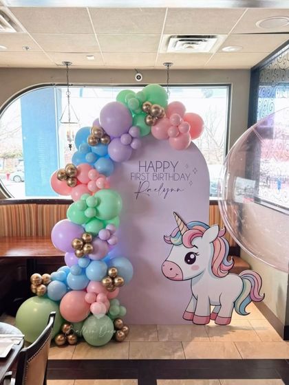 A clean and modern unicorn-themed first birthday with a pastel balloon garland accenting a custom arched backdrop.