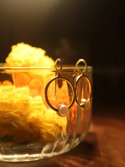 From offering to adornment, it’s a circle that never breaks. These simple and elegant gold-plated hoops with a single pearl rest on a bowl of marigolds.