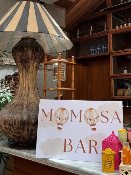 A custom 'Momosa Bar' sign designed for the hot air balloon themed baby shower, adding a playful and personalized touch for the guests.