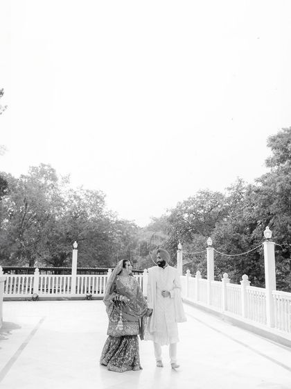 A serene, wide-angle portrait of Kushmeet and Aishwarya. The minimalist composition and black and white tones create a sense of peace and timelessness, focusing on the couple against a clean, architectural backdrop.