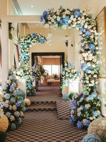 A beautiful floral archway and pathway, decorated with spheres of blue and white flowers, creating a stunning and immersive entrance experience.