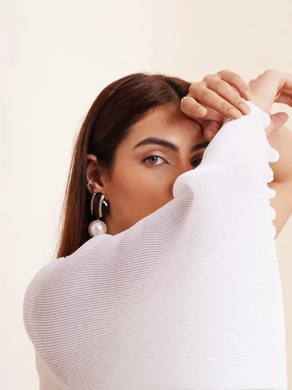 A coy, playful shot where the model peeks out from behind her sleeve. It adds personality and a human element to a fashion lookbook.