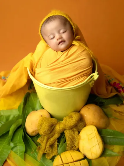 Celebrating the sweetness of summer with a mango-themed newborn shoot. This tiny baby is peacefully sleeping in a bucket surrounded by fresh mangoes.