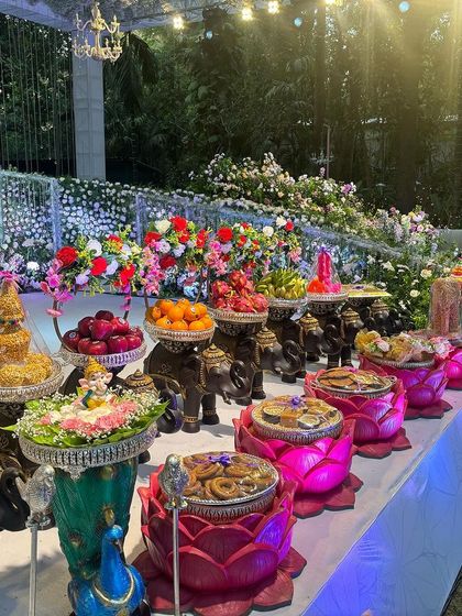 A vibrant offering table with pink lotus bowls and black elephant props.