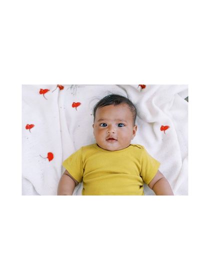 A wide shot of a baby in a yellow top, showing a simple, bright setup for a festive occasion.
