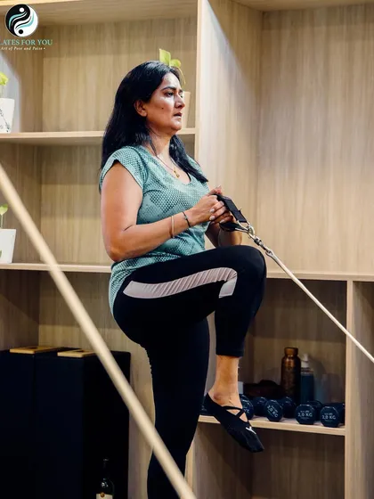 There are a trillion ways to stay fit, but there's nothing as calming as Pilates. This client is performing a standing leg exercise using the tower for resistance and support.