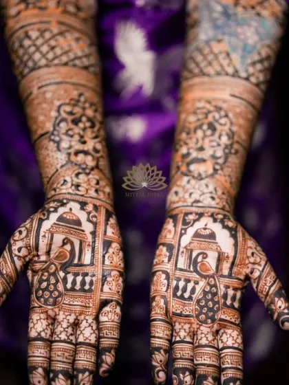 A close-up of the palms of an engagement design, featuring peacocks in a jharokha (window) setting.