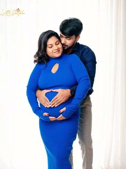A vibrant and joyful studio maternity portrait. The bold blue dress adds a wonderful pop of color, reflecting the couple's happy energy.