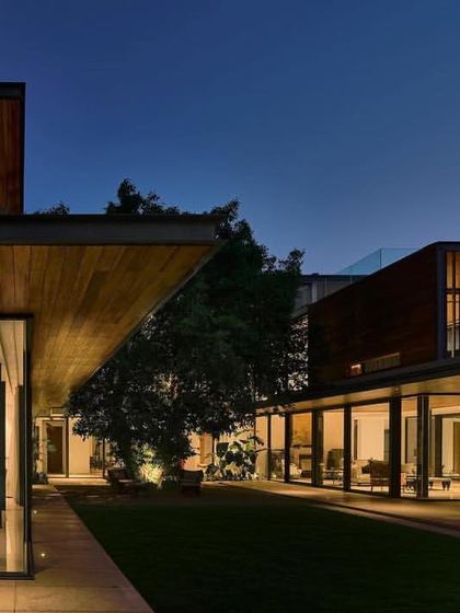 As dusk falls, the 'Patio House' glows from within, highlighting its open plan and the beautiful dialogue between the built form and the central tree.