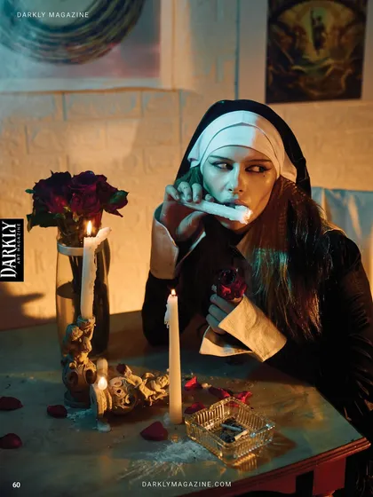 Another moment from the Darkly Magazine editorial. The model's interaction with the props, like the candle and glass, adds to the story of rebellion and dark temptation. The lighting isolates her against the carefully constructed set.