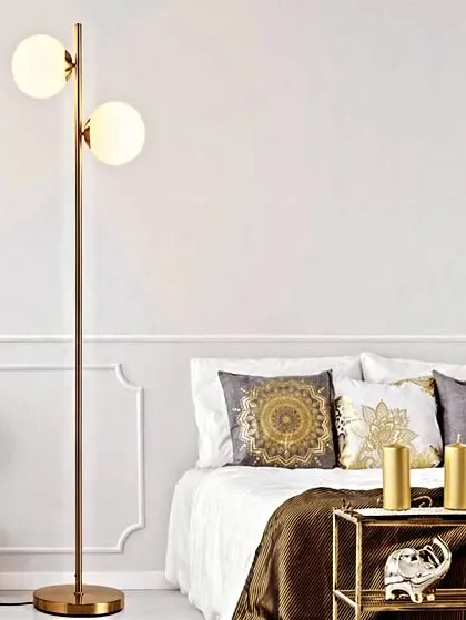 This spruce antique brass floor lamp features two glowing glass globes on a simple, elegant stand. It's a perfect choice for adding a touch of modern sophistication and warm light to a bedroom or living room corner.