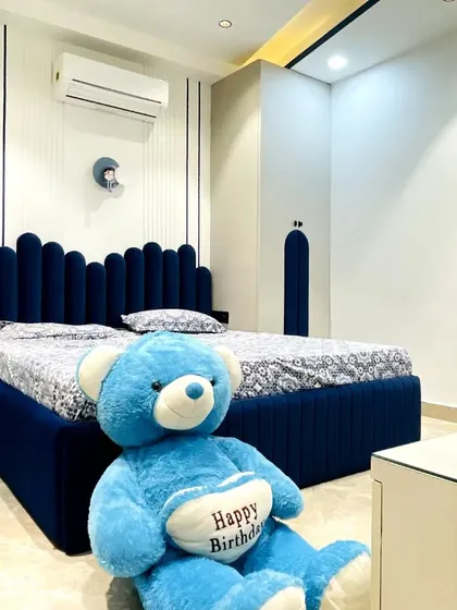 A fun and vibrant bedroom design in shades of blue and white. The custom bed features a unique scalloped headboard that extends to the side panel, creating a playful and cohesive look.