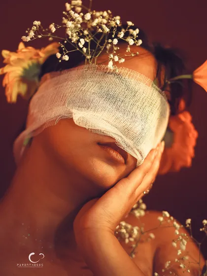 A gentle and vulnerable pose. The hand to her cheek adds a human touch to the surreal, floral concept.