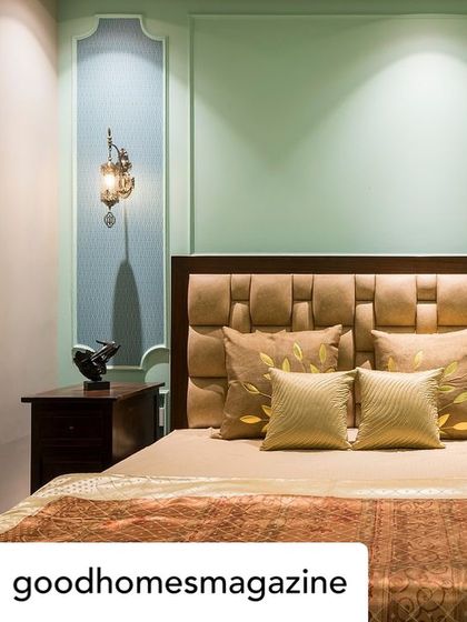 A bedroom from our featured project in Goodhomes magazine. The design uses a soft pastel blue-green on the walls, classic molding, and a textured headboard to create an English-inspired, tranquil space.