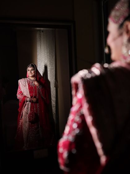 A beautiful mirror shot of a Nikkah bride. This artistic photo captures her serene expression and the elegance of her traditional red outfit.