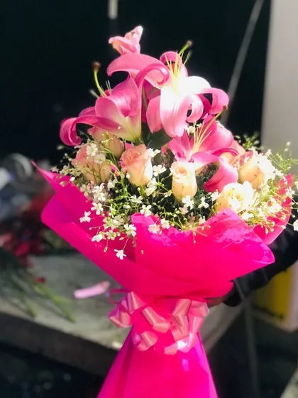 A vibrant bouquet combining bright pink lilies and soft roses, wrapped in matching pink paper. This is a very popular choice for birthdays and anniversaries.