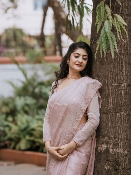 A serene outdoor portrait of the bride in a beautiful pastel saree. Her calm expression and the natural setting create a peaceful and elegant image.