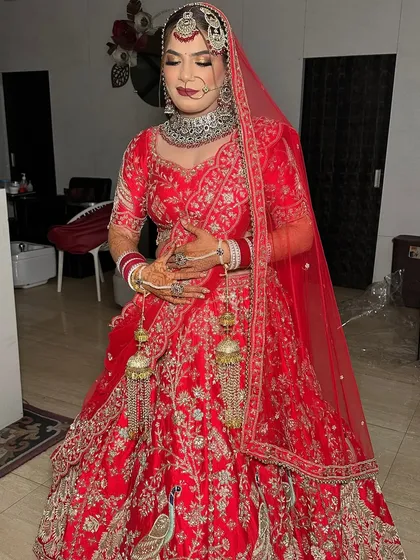 This bride looks absolutely timeless in her red bridal lehenga. The makeup features a classic red lip and defined eyes, paired with heavy silver and pearl jewelry.