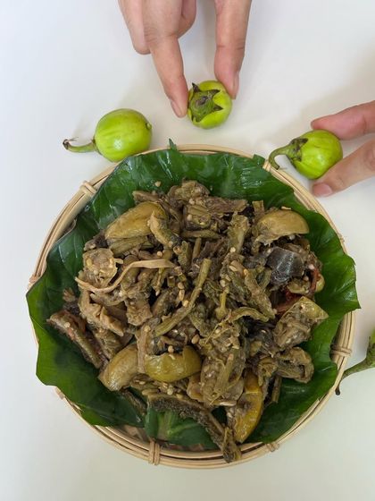 A plated serving of 'Rusep', garnished with the small, green bitter eggplants used to make it. It's a dish that truly represents the wild and foraged aspect of our cuisine.
