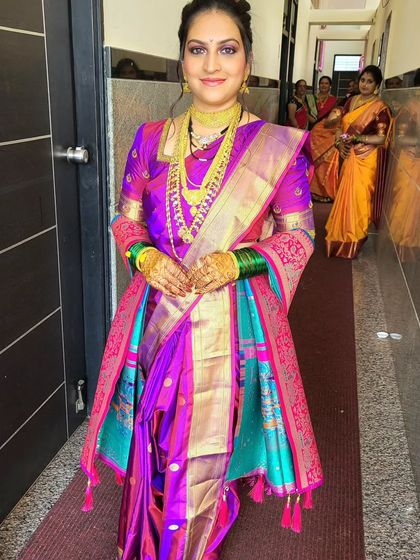 A beautiful Marathi bride, Sonia, in a traditional Nauvari saree for her wedding. The vibrant purple and pink saree is draped to perfection, ready for the ceremony.