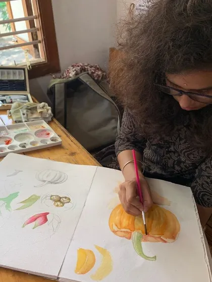 A student works on a watercolor painting of a pumpkin. The learning process involves failures and successes, but sticking with it is how beautiful results are achieved.