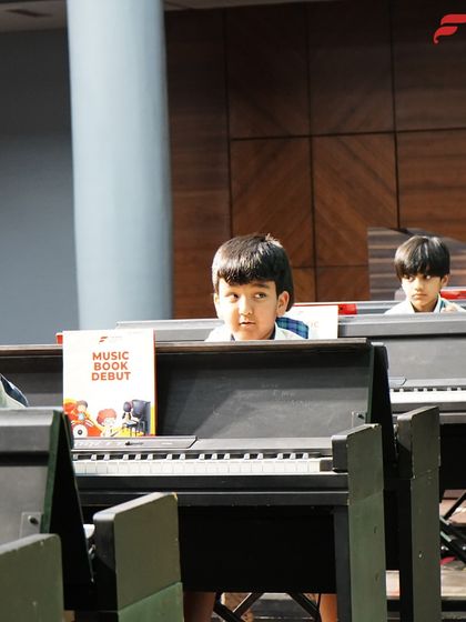 Curiosity and engagement in the music lab. These young students peer over their keyboards, fully immersed in the lesson, showcasing how our program captures the attention of even the youngest learners.