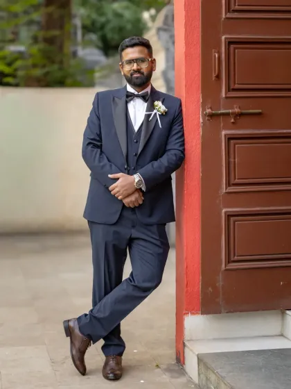 A relaxed and confident portrait of the groom leaning against a wall before the ceremony. He looks calm and ready.