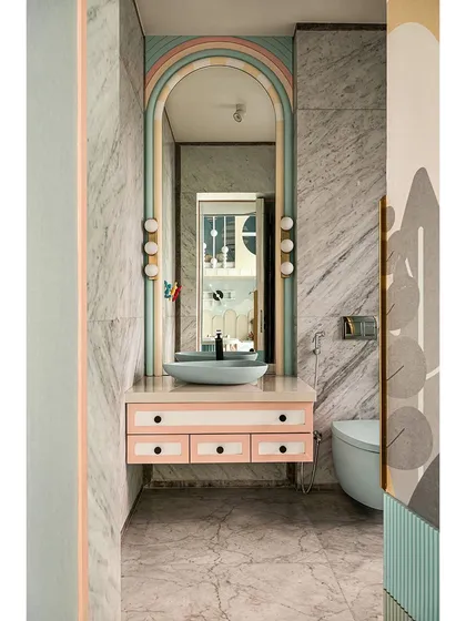 The bathroom attached to the kids' room continues the playful theme with a pastel-colored vanity and a rainbow-arched mirror. It's a fun and functional space designed just for them.