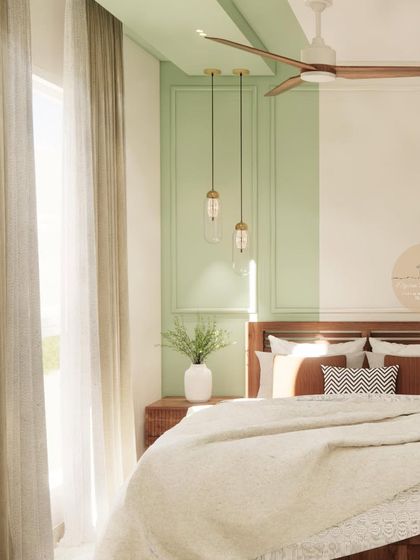 A guest bedroom design featuring a mint green accent wall with molding, sheer curtains, and warm pendant lights, creating a fresh and inviting space.