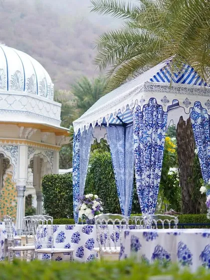 A wide view of the outdoor seating area, with custom canopies and patterned tablecloths creating a cohesive and elegant look. The backdrop of the palace architecture adds to the grandeur.