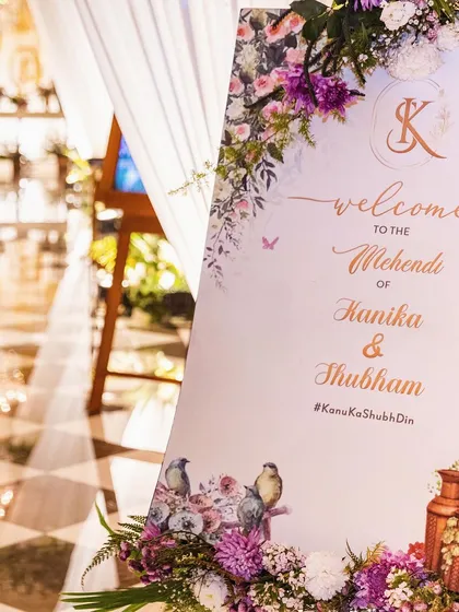 A close-up of the beautifully designed welcome sign for the Mehendi, featuring a soft floral design and the couple's custom wedding hashtag.