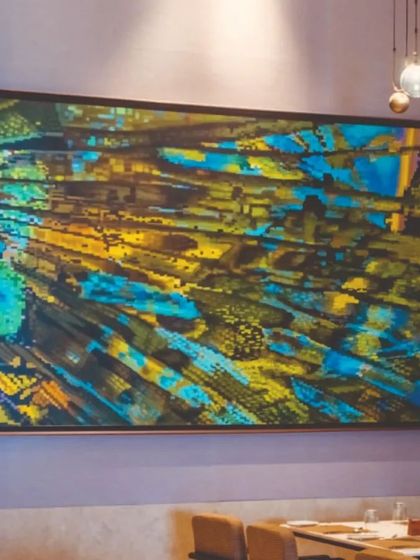 An abstract piece with vibrant blues and yellows installed in a dining area at JW Marriott. The artwork is positioned to be a conversation starter, adding a dynamic layer to the guest experience.