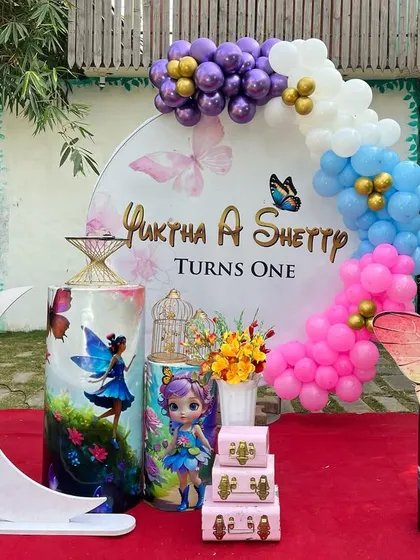 This is a duplicate of ID 2. A magical butterfly and fairy theme for a first birthday. This outdoor setup includes a personalized circular backdrop, a pastel balloon garland, and themed props.