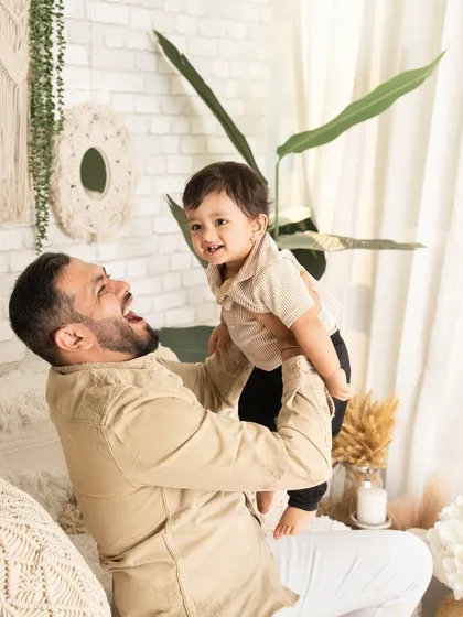The pure joy of being lifted up by dad. This candid shot captures a moment of laughter and play during a relaxed, modern family session.