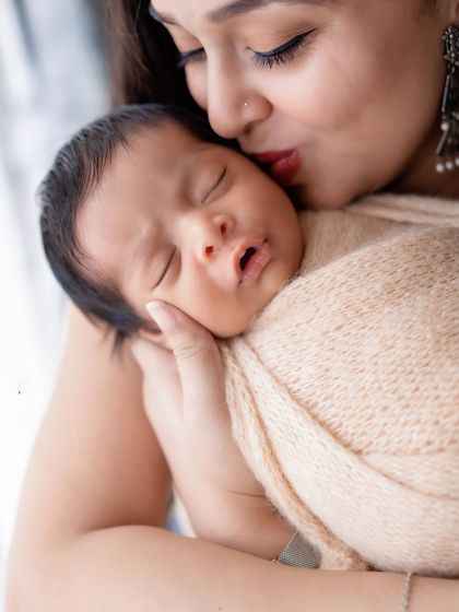 A mother's gentle kiss for her sleeping newborn. A close-up shot that is full of love and tenderness.