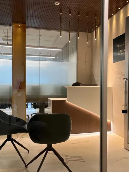 This view from the entrance of the law office frames the reception area, highlighting the layered design of glass, marble, and warm wood tones that create an inviting yet professional atmosphere.