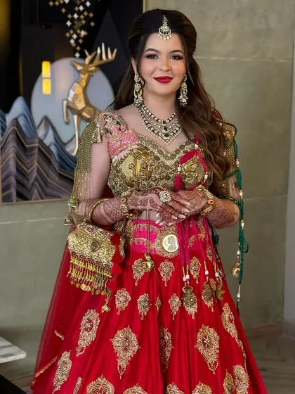 The bride looks like royalty with her hair in a classic half-up style, perfectly complementing her traditional red and gold lehenga.
