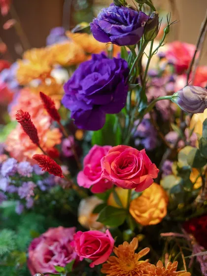 A detailed close-up of a floral arrangement, showcasing the rich textures and colors of each bloom. I carefully select each flower, from the deep purple lisianthus to the bright pink roses, to create a harmonious composition.
