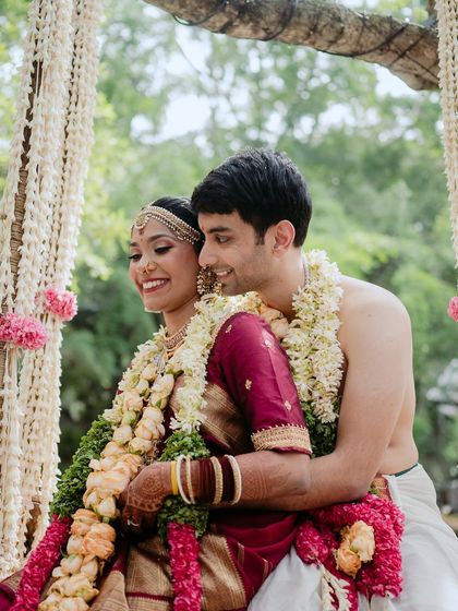 An embrace on the floral swing, a perfect shot for any pre-wedding or wedding album. The garlands and the couple's traditional attire create a beautiful picture.