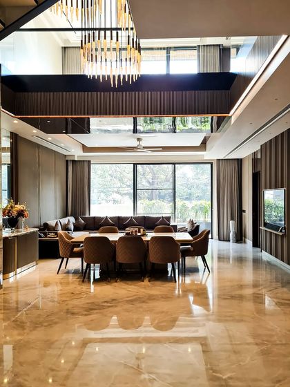 The completed double-height dining and living area. The dramatic chandelier draws the eye upward, while the warm wood paneling and marble floors create an atmosphere of sophisticated comfort.