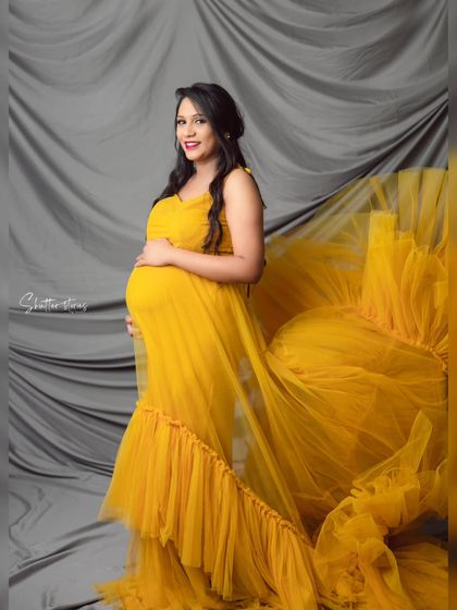 The dramatic flair of the yellow tulle gown is captured perfectly as it flows behind the mom-to-be in this dynamic studio shot.