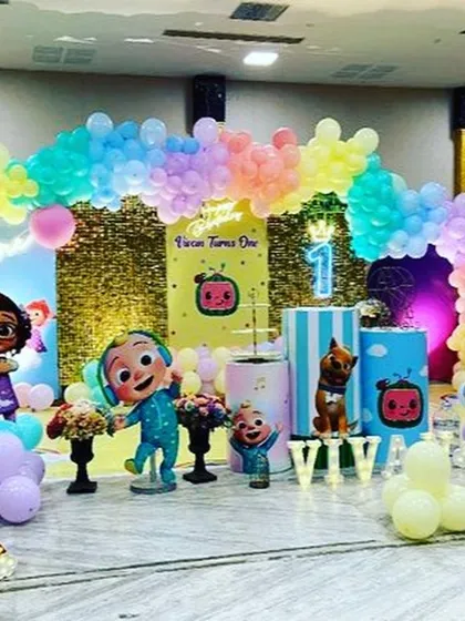 Another take on the Cocomelon theme, this setup features a gold shimmer wall, a pastel rainbow balloon arch, and a neon "One" sign for a touch of sparkle.