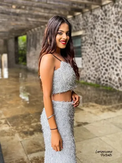 A happy and confident portrait in a hallway, the model's smile is infectious as she shows off her unique silver party dress.
