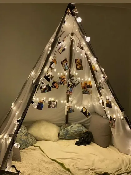 A cozy and personal cabana tent decorated with fairy lights and strings of memorable photos. This creates an intimate and sentimental space for a couple to celebrate a special occasion.