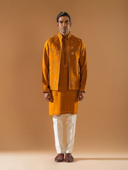 A rich mustard-yellow jacket and kurta set. The jacket is embellished with delicate floral embroidery, adding a layer of texture and sophistication to the monochromatic ensemble.