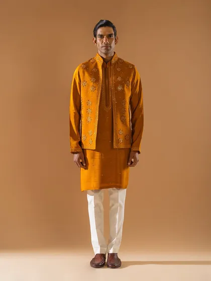 A rich mustard-yellow jacket and kurta set. The jacket is embellished with delicate floral embroidery, adding a layer of texture and sophistication to the monochromatic ensemble.