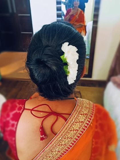 A traditional low bun, or juda, adorned with a simple line of white flowers. This is a timeless and graceful hairstyle for wearing with a saree.