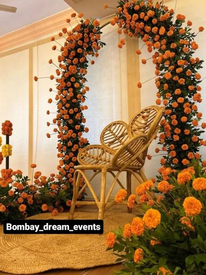 For a boho-chic Mehndi, this peacock-style cane chair (`jhoola`) is paired with a beautiful arch of fresh orange marigolds.