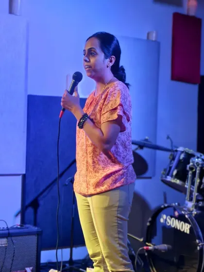A poet sharing her work under the soft lights. Our open mic is a safe and encouraging space for poets and writers to perform their original pieces.